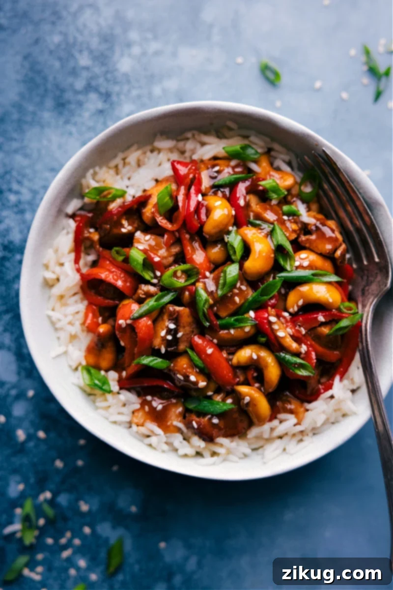 The Best Saucy Cashew Chicken A vibrant bowl of homemade Cashew Chicken, garnished with fresh green onions and sesame seeds, ready to be enjoyed.