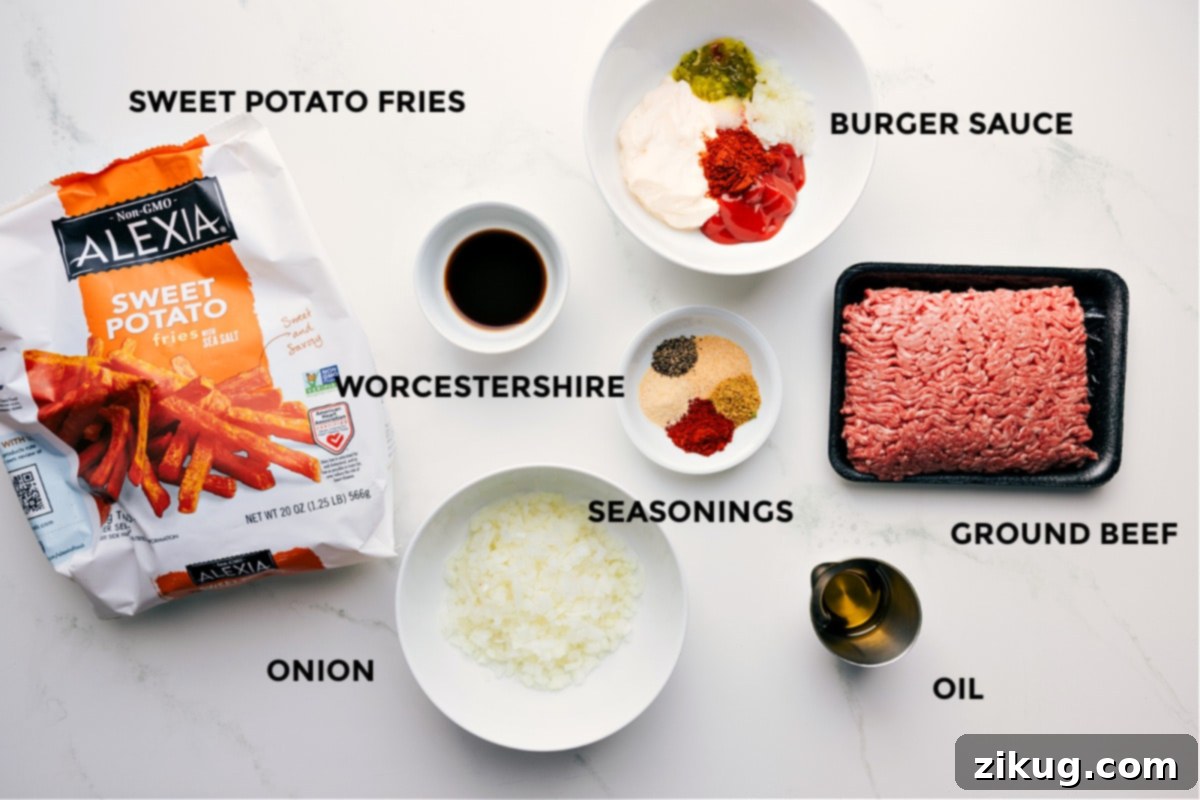 A collection of prepped ingredients for making the burger bowls, including sweet potato fries, a bowl of homemade burger sauce, Worcestershire sauce, various spices, fresh ground beef, olive oil, and diced onion.