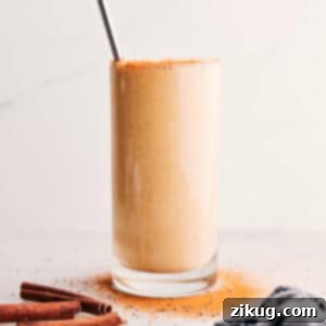 A tall glass of Golden Milk Smoothie garnished with a straw and a sprinkle of spices.
