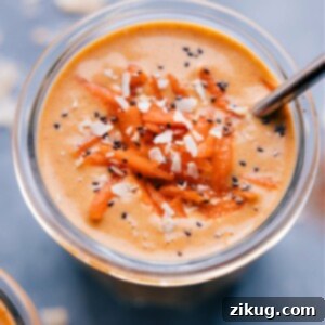 Sunshine Carrot Blend 3 A tall glass of a creamy, orange Carrot Smoothie, garnished with a sprinkle of cinnamon and a fresh mint leaf. The texture appears thick and inviting.