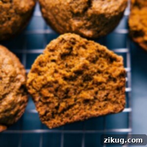 A close-up shot of two Healthy Carrot Muffins on a white background, one whole and one cut in half.