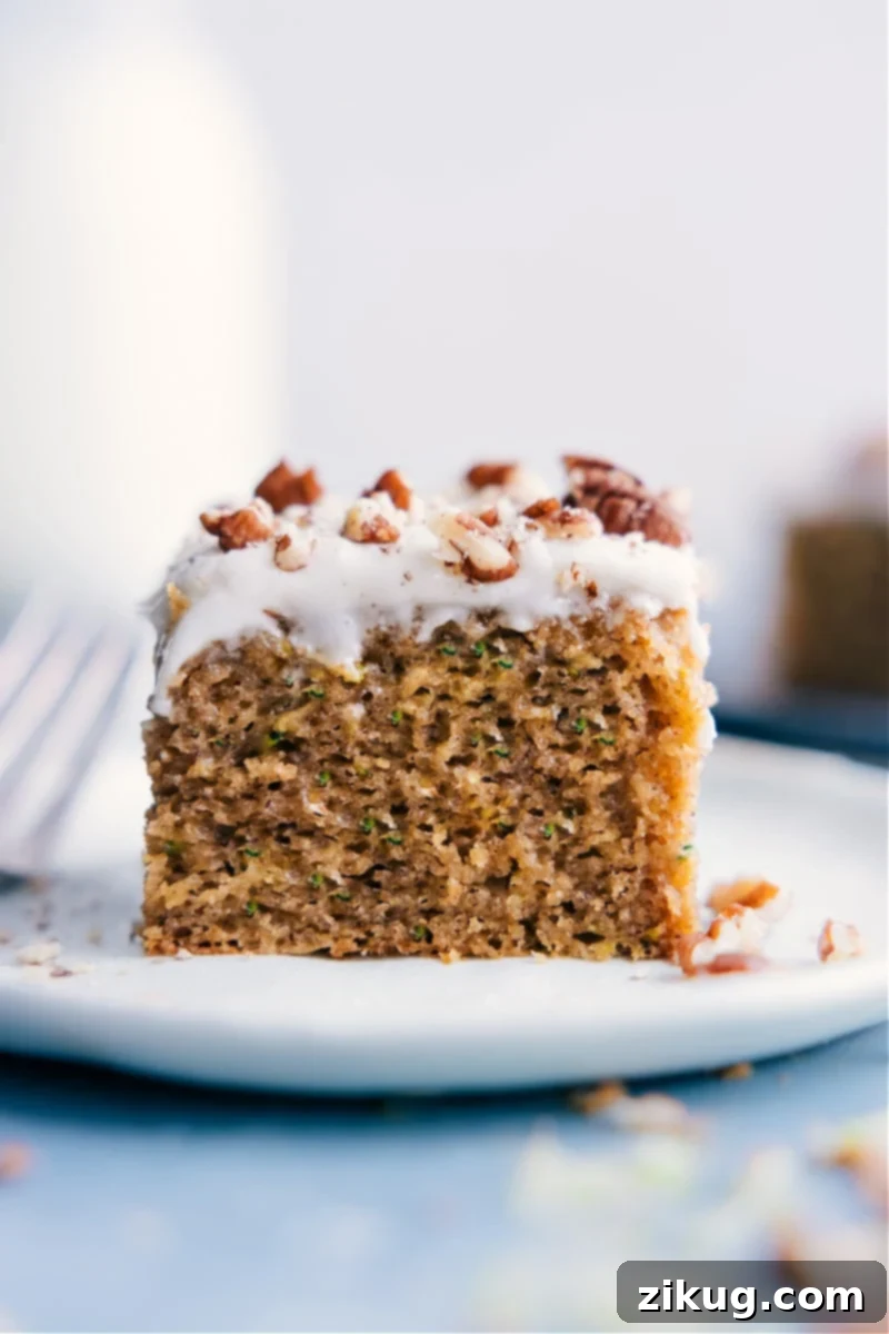 A slice of moist Healthy Zucchini Cake with cream cheese frosting on a plate, showcasing its delicious texture.
