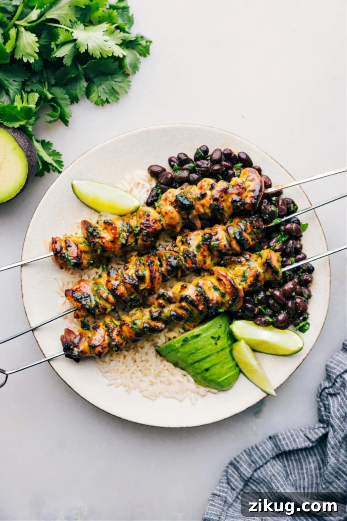 Citrus Chicken Marinade on a plate over rice, garnished with fresh herbs and lime wedges.