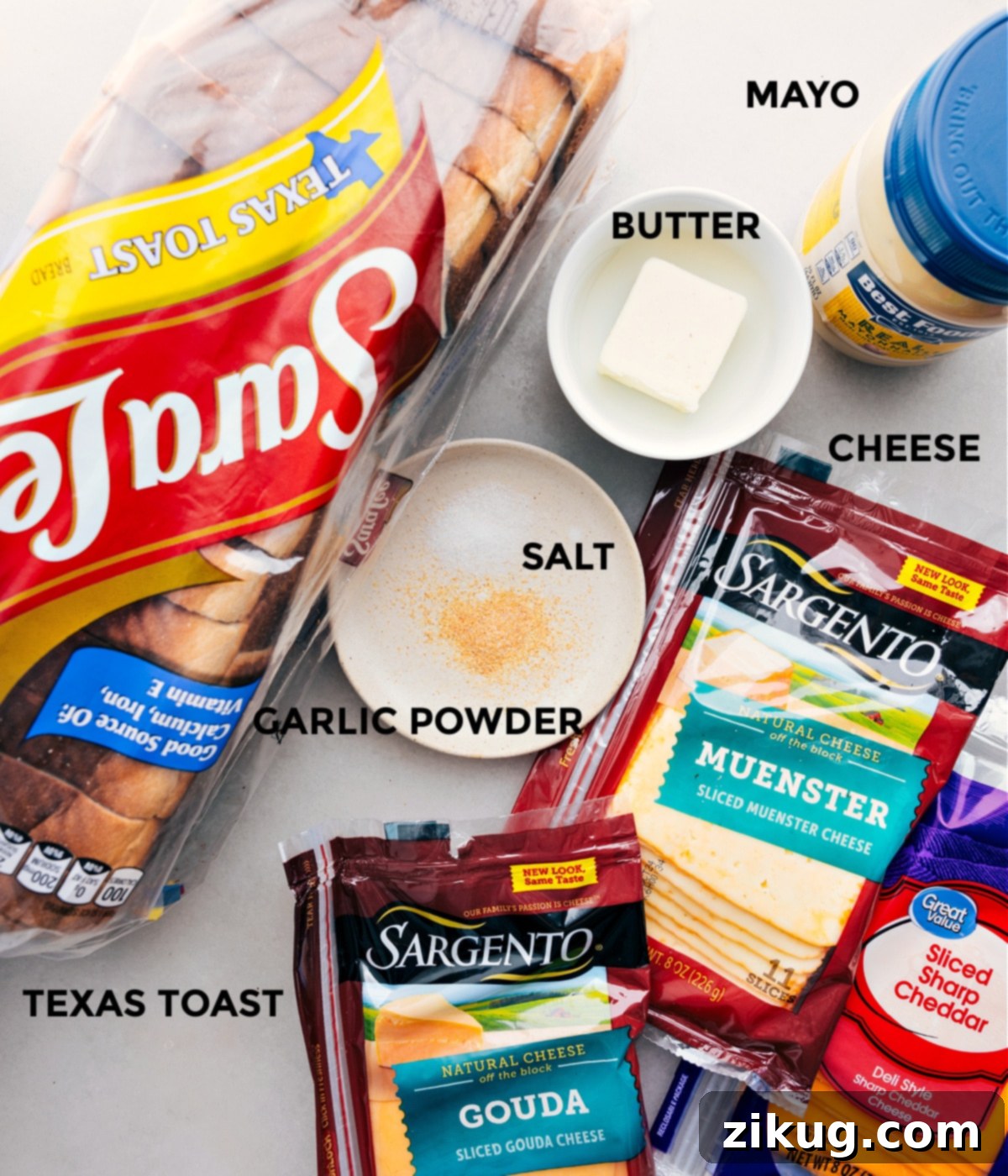 All the essential ingredients for making grilled cheese: bread, cheddar, muenster, gouda, mayo, butter, and seasonings, prepped and ready for assembly.