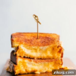 Grilled Cheese stacked on top of each other showing the cheesy center, golden-brown and delicious.