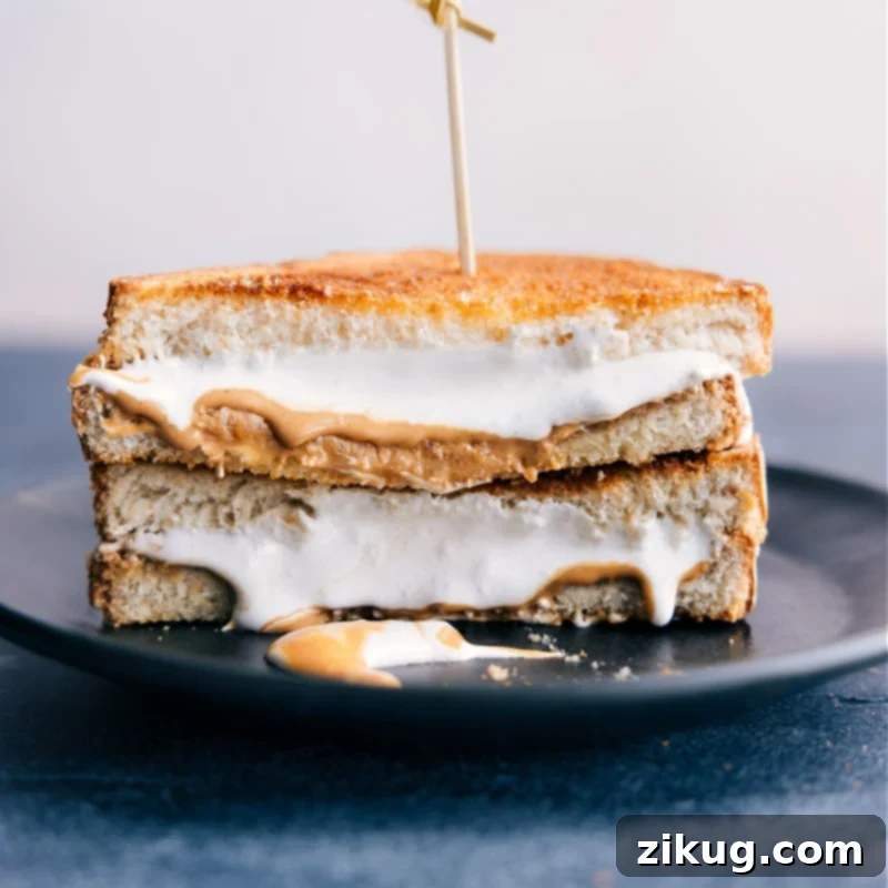 Discover the delightful combination of peanut butter and marshmallow fluff, air-fried to perfection! This Air Fryer Sandwich recipe is a quick, easy, and best after-school snack or dessert. An appetizing image of an Air Fryer Peanut Butter and Marshmallow Fluff Sandwich cut in half, revealing the perfectly melted marshmallow fluff and peanut butter nestled within a crispy, golden-brown bread.