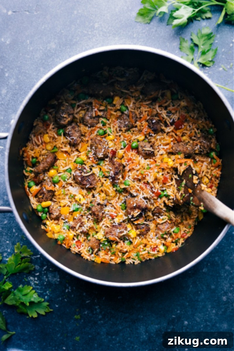 Delicious One-Pot Meatballs and Rice: Tender mini meatballs, fluffy rice, vibrant veggies, and a spectacular spice blend make this a family favorite. Perfect for a quick and easy weeknight comfort meal. #dinner #quick #easy #comfortfood #familyfriendly #kidfriendly #meatballs #rice Overhead image of a skillet brimming with One-Pot Meatballs and Rice, garnished with fresh herbs. The photo highlights the tender meatballs, perfectly cooked fluffy rice, and a colorful array of vegetables.