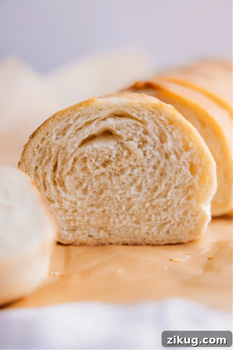 Delicious homemade French Bread, light and fluffy inside with a crusty outside A perfectly baked, golden-brown French bread loaf with a visible slice showing its soft interior