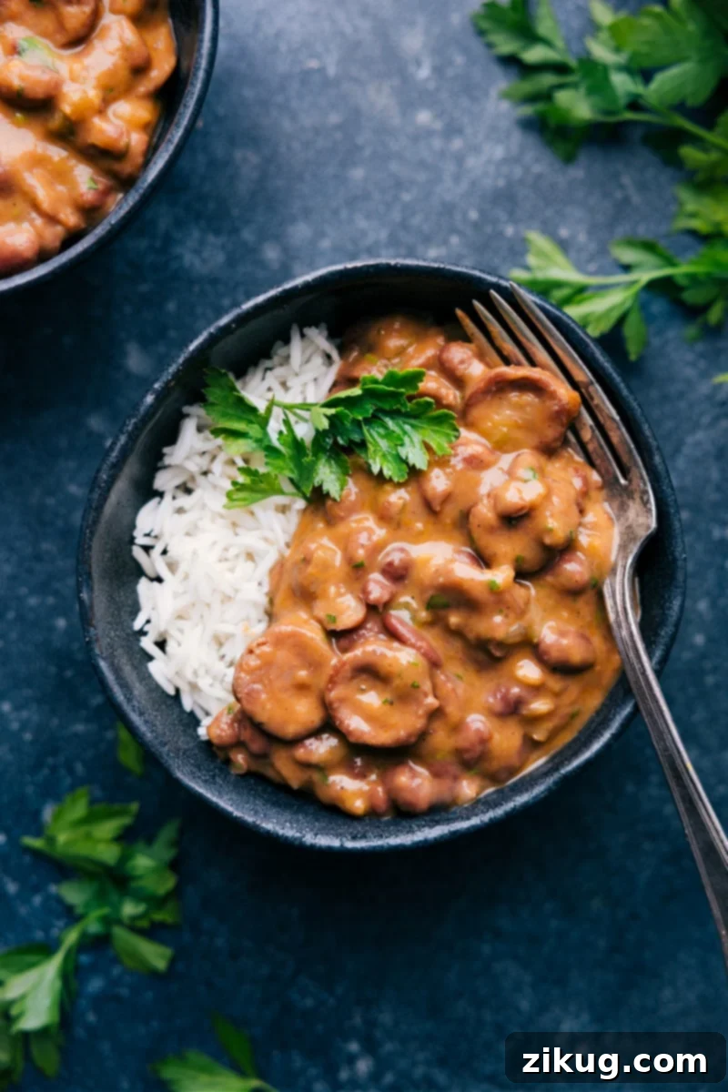 Hearty Red Beans And Rice: Andouille sausage, creamy red beans, and vibrant vegetables in a rich, flavorful sauce. A perfect comfort meal. A steaming bowl of classic Red Beans and Rice, garnished with fresh parsley, alongside crusty bread