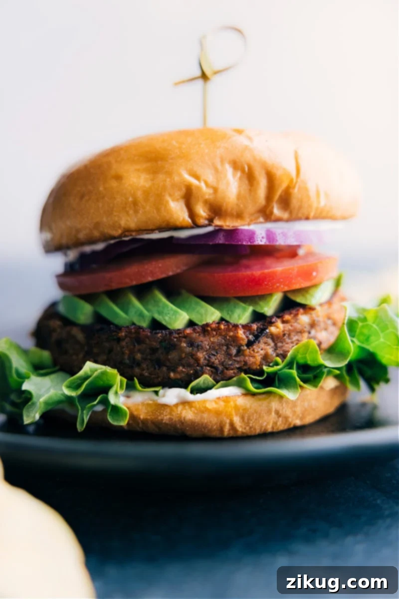 These Sweet Potato Black Bean Burgers are insanely good -- they're robustly flavored, thick & hearty (without being soggy!), and easy to make thanks to a few short-cuts. Recipe via ChelseasMessyApron #dinner #quick #easy #simple #best #veggies #familyfriendly #kidfriendly #sweetpotato #blackbean #burger A perfectly cooked Sweet Potato Black Bean Burger served on a bun with fresh toppings on a plate, showcasing its appealing texture and robust appearance.