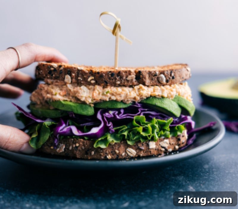 Enjoying a delicious Buffalo Chickpea Salad Sandwich: a quick, healthy, and flavorful vegetarian meal option for any time of day. A beautifully composed Buffalo Chickpea Salad Sandwich, perfectly assembled with fresh toppings and a generous filling, captured just before being enjoyed as a quick and healthy meal.
