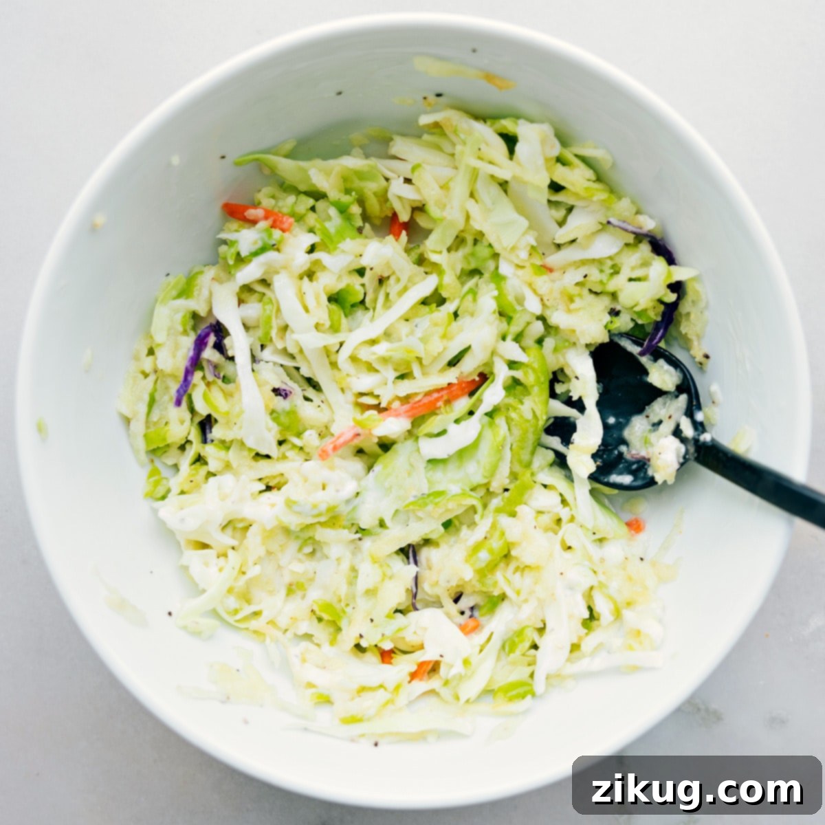 How To Make Healthy Turkey Wraps Close-up shot of the apple coleslaw mixture being stirred in a bowl, showcasing its readiness for the turkey wraps.