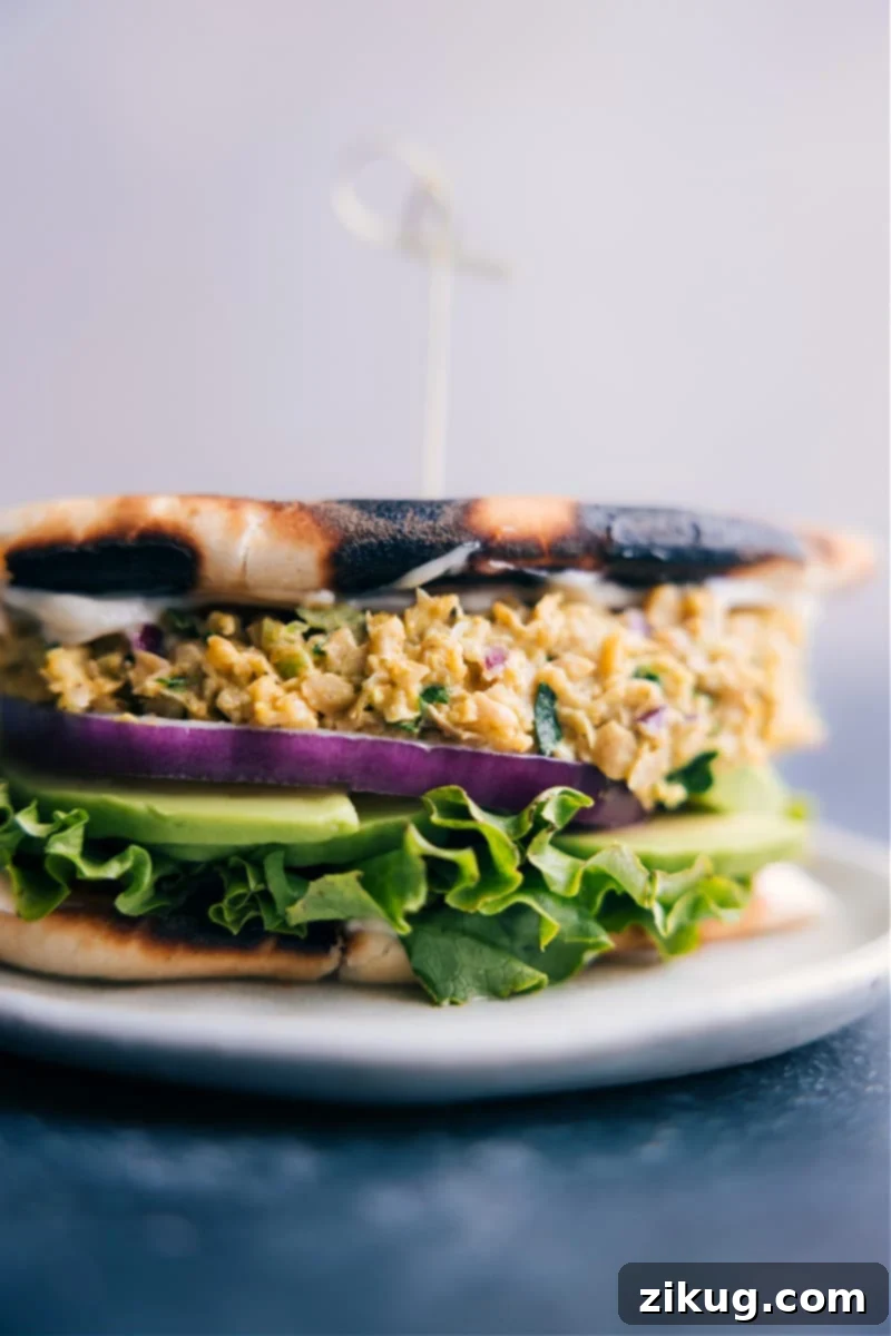Image of a Curried Chickpea Sandwich on a plate, garnished with fresh herbs