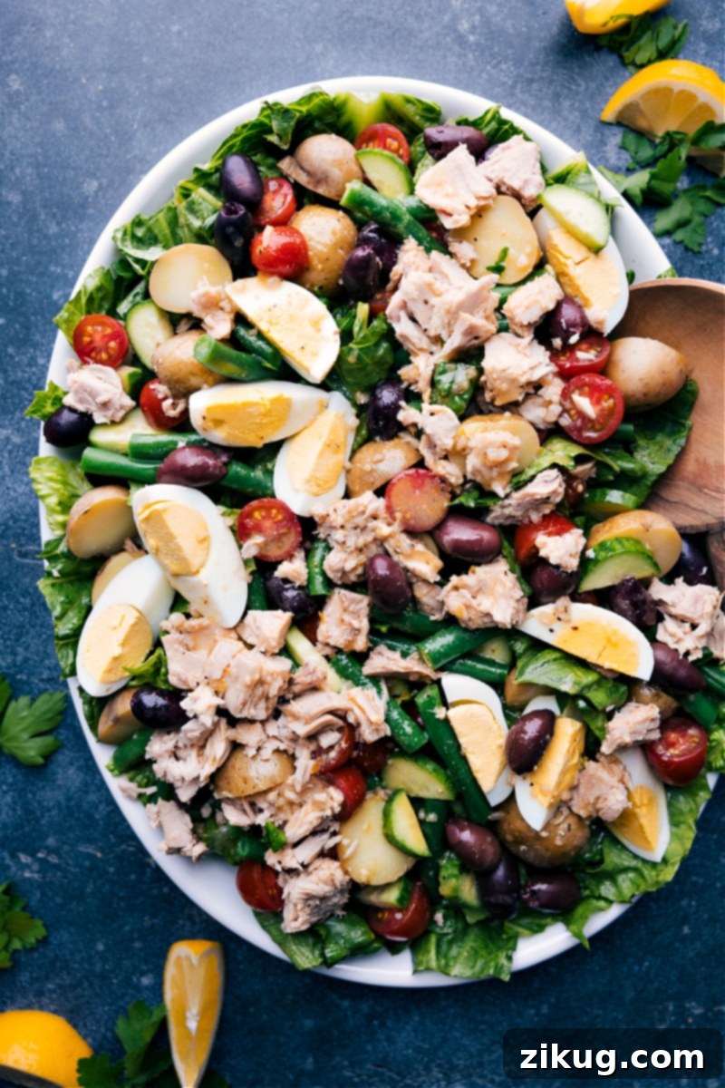 Tuna Niçoise Salad! The salad greens are topped with a myriad of veggies and potatoes, olive-oil packed tuna fish and the best light lemon vinaigrette ties everything together beautifully. Recipe via ChelseasMessyApron #lunch #dinner #quick #easy #simple #healthy #clean #cleaneating #whole30 #seafood #familyfriendly #kidfriendly #tuna #nicoise #salad Overhead image of the dressed salad ready to be enjoyed