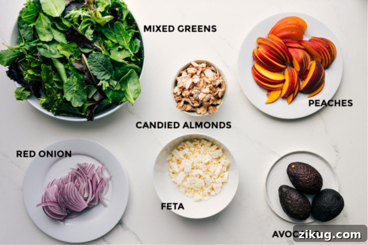 Ingredients In Peach Salad All ingredients for the peach salad are neatly prepped and arranged, including fresh mixed greens, vibrant red onions, creamy feta, golden candied almonds, perfectly ripe avocados, and sliced peaches, ready for assembly.