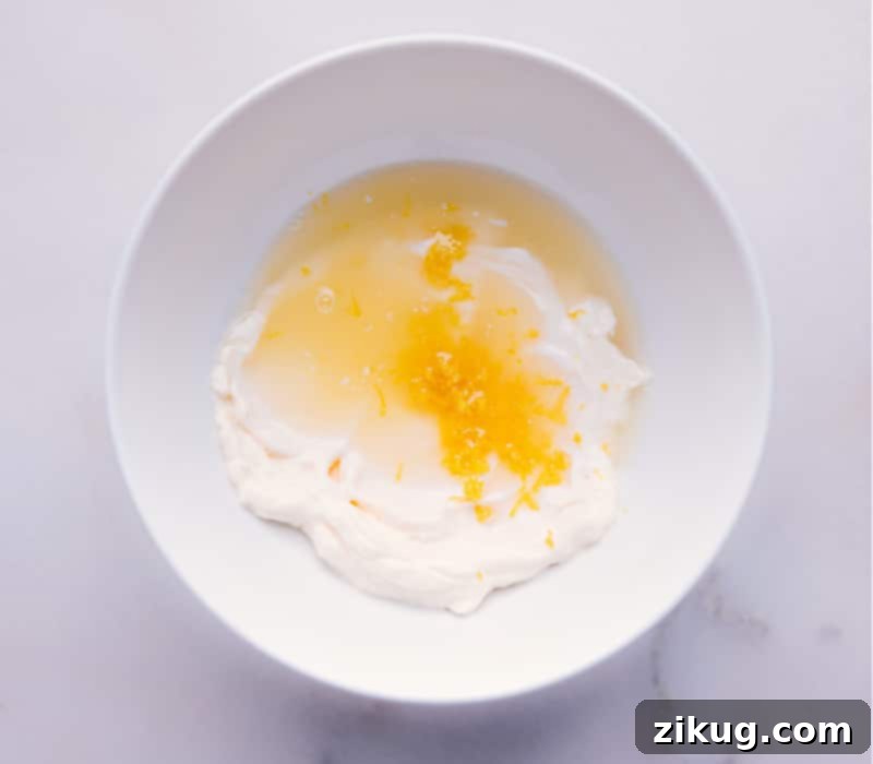 Close-up image of ingredients being added to a bowl, showing the creamy mayonnaise, relish, and fresh dill.