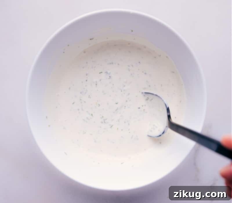 A beautiful shot of the finished homemade Tartar Sauce in a rustic ceramic bowl, garnished with a sprig of fresh dill.