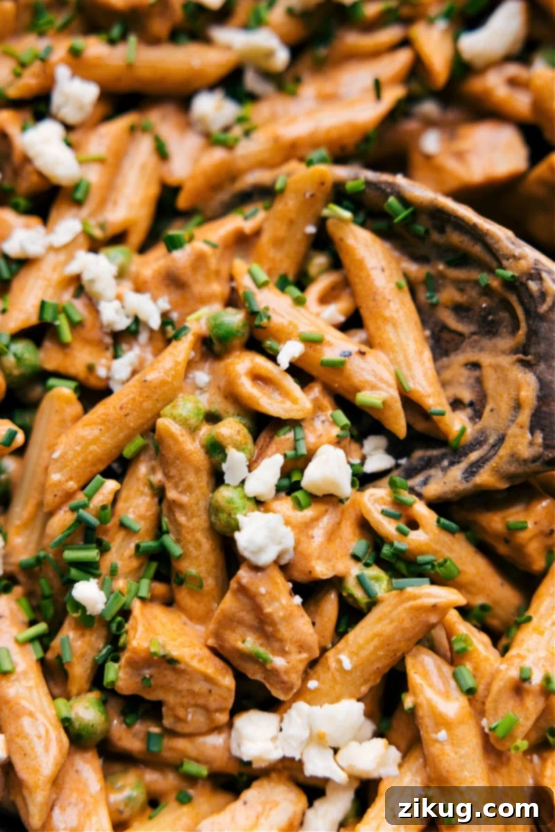 Overhead image of creamy and spicy Buffalo Chicken Pasta garnished with blue cheese and green onions, served in a wide bowl.