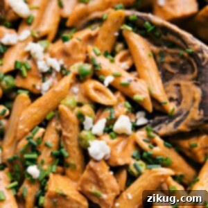 A bowl of creamy Buffalo Chicken Pasta topped with blue cheese crumbles and fresh green onions.