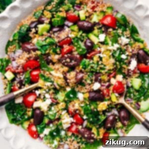 A close-up image of a bountiful Greek Quinoa Salad, featuring vibrant vegetables, fluffy quinoa, and crumbled feta cheese, with a lemon-Greek dressing.