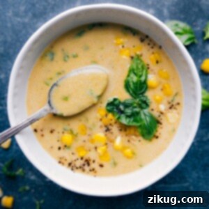 Close-up of a serving of creamy corn soup with fresh basil garnish.