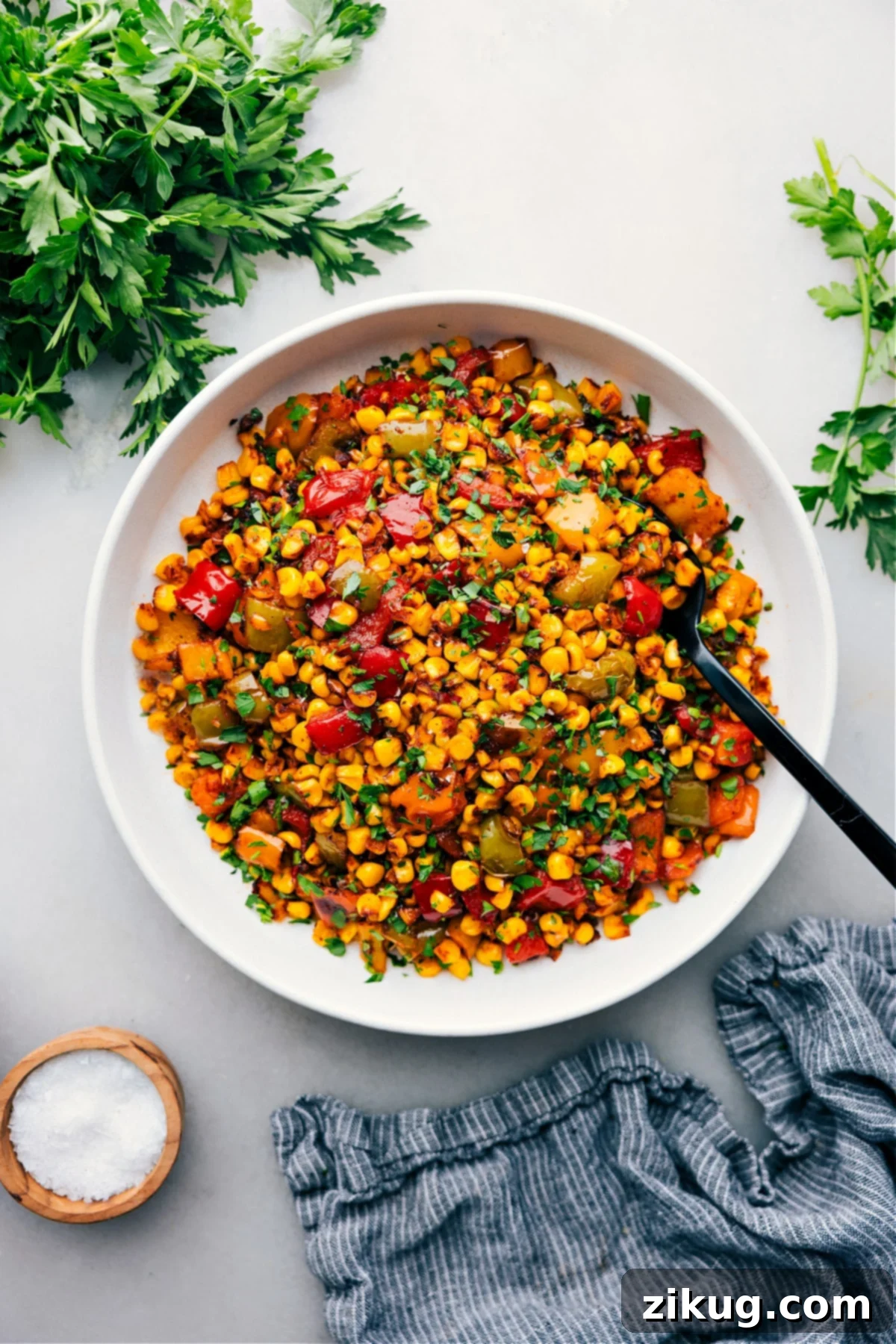 The Best Summer Roasted Corn Recipe A bowl of freshly roasted corn with sweet peppers, garnished with cilantro, ready to be served at your next BBQ or summer event.