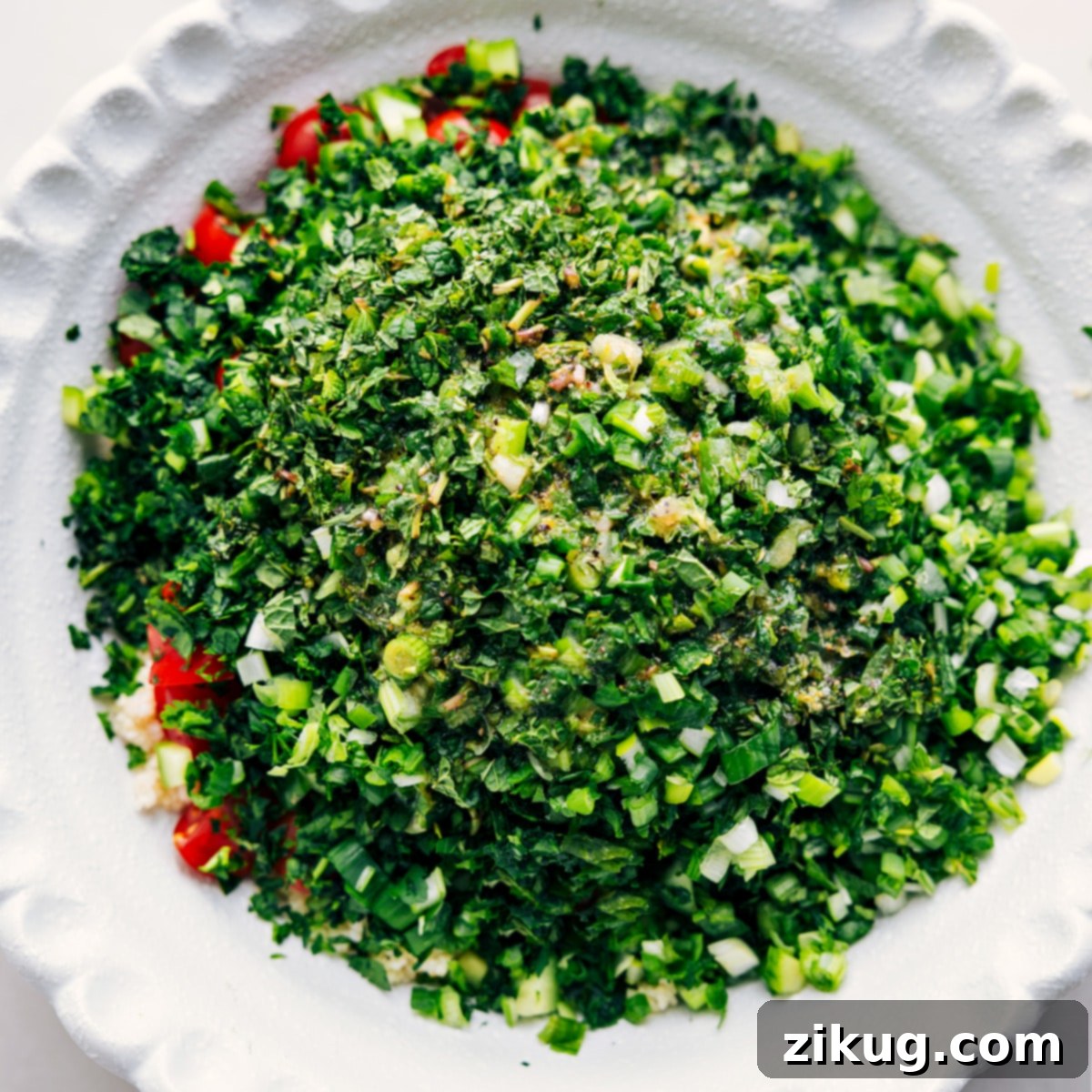 All the fresh ingredients—bulgur, cucumbers, tomatoes, mint, parsley, and green onions—mixed in a large bowl, ready to be tossed with the zesty dressing and enjoyed.