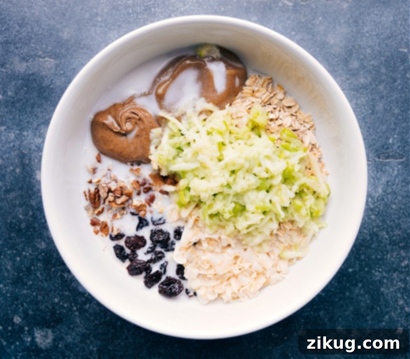 Bircher Muesli is one of my favorite hearty and nutritious breakfast recipes! Recipe via chelseasmessyapron #breakfast #best #quick #easy #simple #healthy #cleaneating #oats #bircher #muesli Process shots of Bircher Muesli- image of the apple and milk being added to the bowl