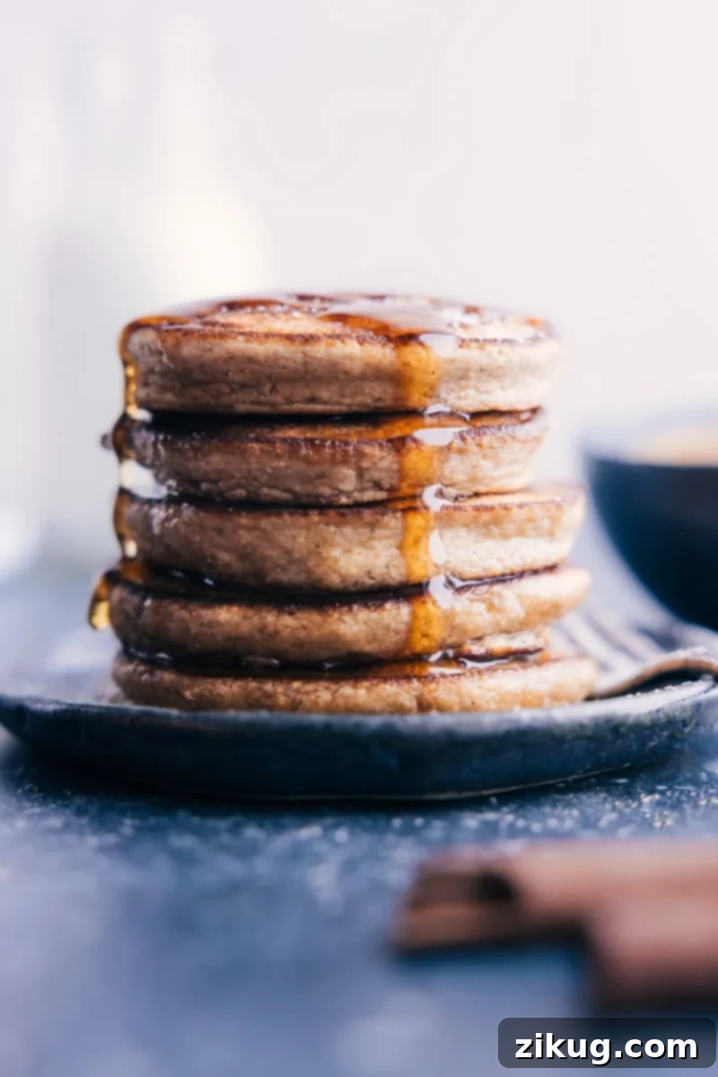 Healthy, Quick, Easy & Simple Applesauce Pancakes - A Family-Friendly & Kid-Friendly Blender Pancake Recipe for Brunch or Breakfast A stack of golden brown Applesauce Pancakes, drizzled with maple syrup and topped with fresh apple slices, ready for a delicious breakfast.
