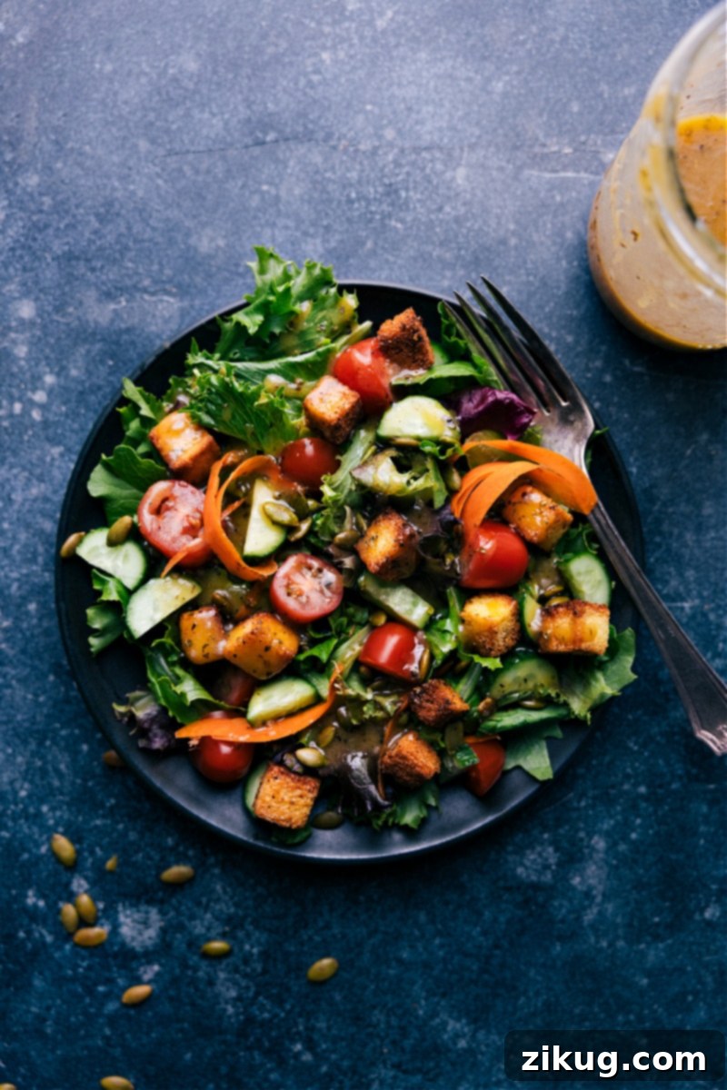 Master the art of homemade vinaigrette! This easy-to-follow recipe transforms simple ingredients into the ultimate salad dressing, perfect for salads, roasted veggies, or as a light marinade for proteins. #VinaigretteRecipe #HomemadeDressing #SaladGoals #HealthyEating #KitchenStaple Overhead view of a fresh green salad generously drizzled with homemade vinaigrette, ready to be served.