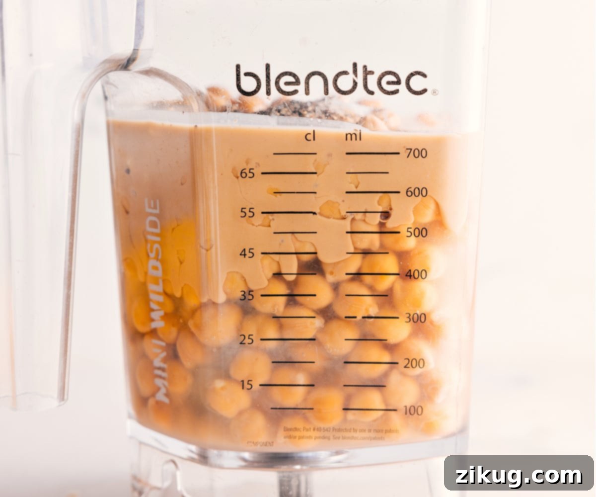 All the core ingredients – chickpeas, tahini, fresh lemon juice, and garlic – are perfectly combined in a high-powered blender, poised for transformation into exceptionally smooth and creamy hummus.