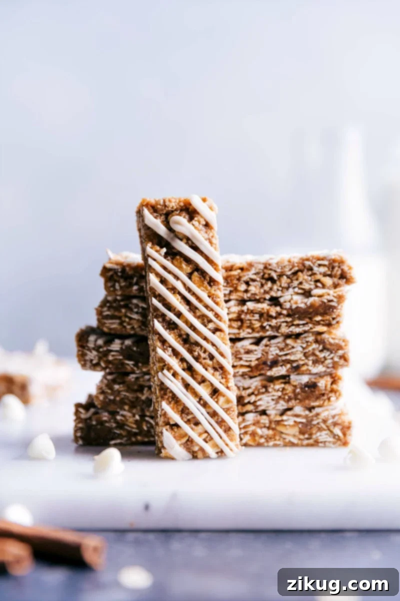 These Oatmeal Granola Bars are made to taste like an iced oatmeal cookie! Recipe via ChelseasMessyApron #quick #easy #snack #best #simple #glaze #oats #healthy #kidfriendly #oatmeal #granola #bars Close-up of a single no-bake oatmeal granola bar with a delicate white chocolate glaze, highlighting its soft texture.