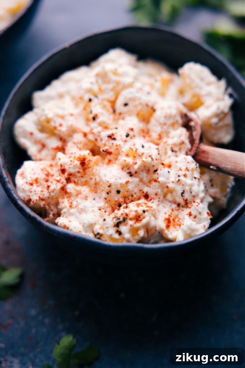Overhead view of perfectly creamy potatoes, garnished with paprika and fresh herbs, in a serving bowl.