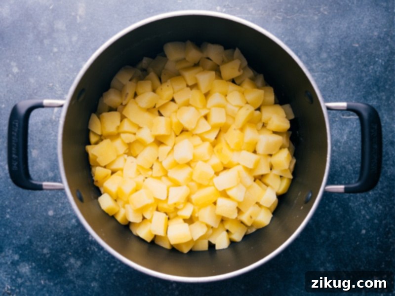 Overhead view looking into a pot of perfectly cooked and diced potato cubes, ready for the sauce.