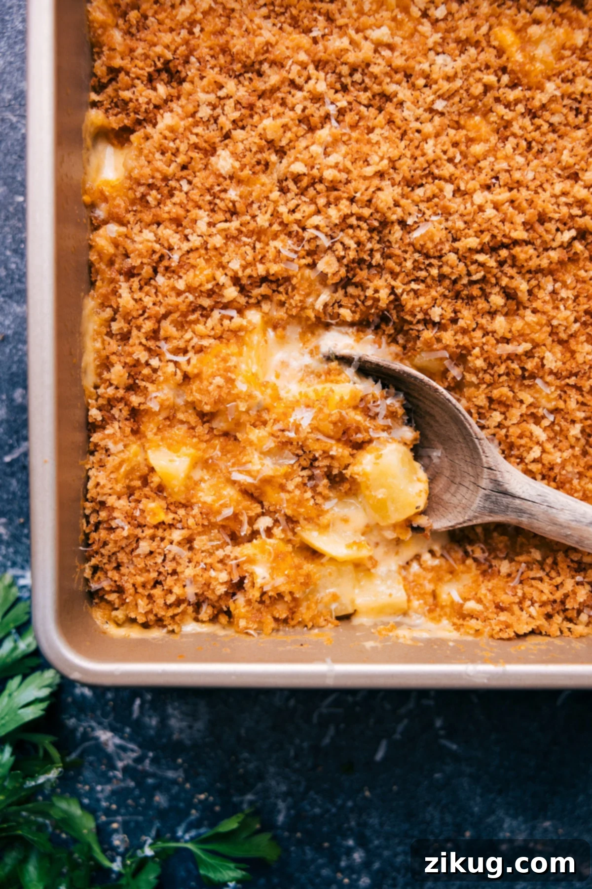 Freshly baked Cheesy Potatoes with a big scoop ready to serve, showing the golden crust and creamy interior.