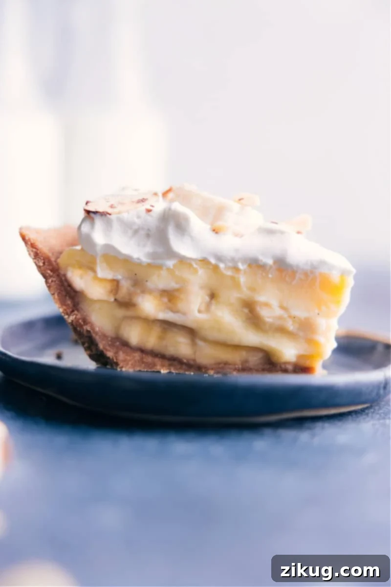 The ultimate Banana Cream Pie: a buttery graham cracker crust, creamy banana custard, and sweet whipped cream. Recipe via chelseasmessyapron #dessert #best #quick #easy #simple #treat #thanksgiving #familyfriendly #bananacream #pie Image of a beautiful slice of Banana Cream Pie with whipped cream and a graham cracker crust