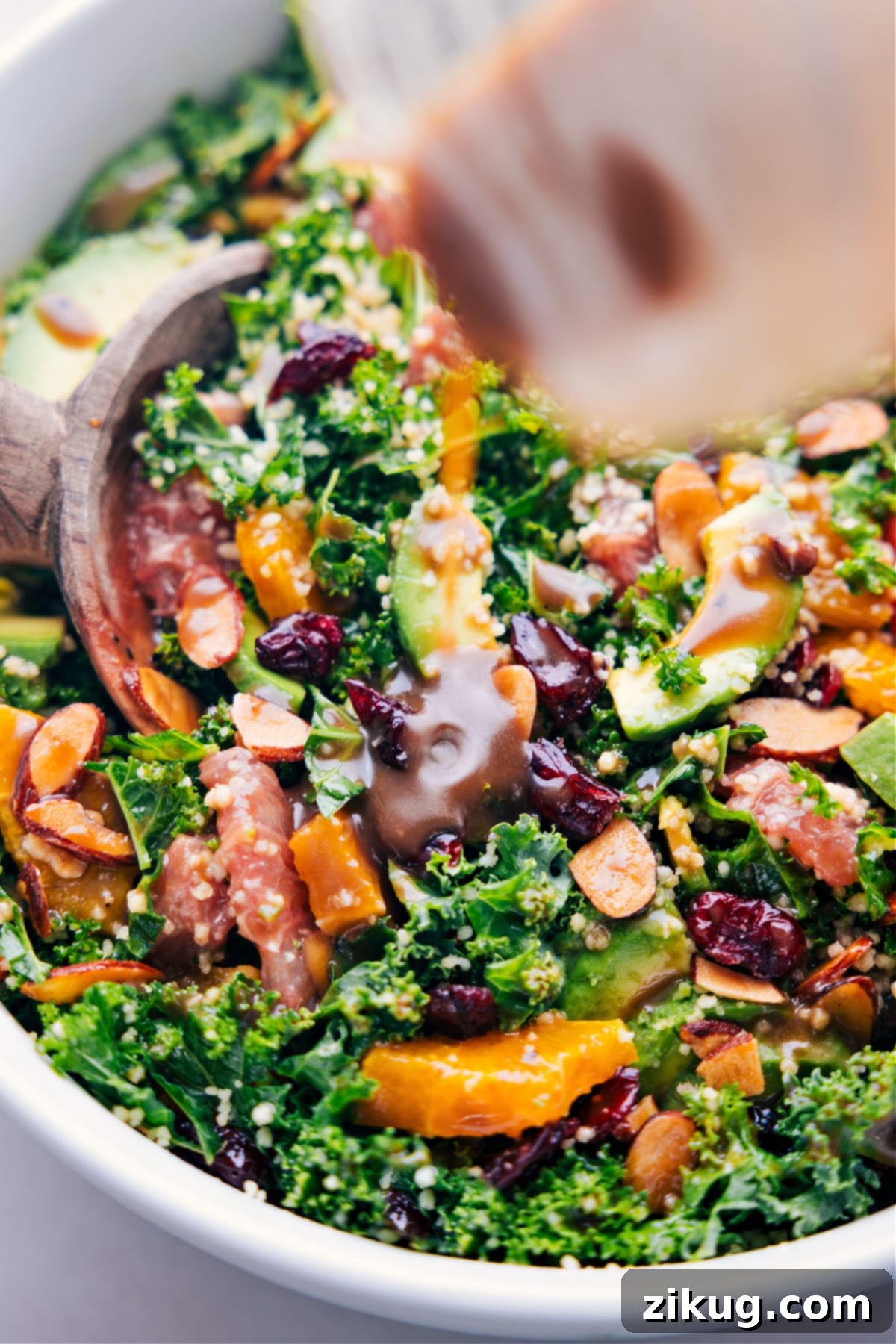 The Best Grapefruit Salad Recipe Balsamic dressing being poured generously over the vibrant, freshly assembled grapefruit salad in a large bowl.