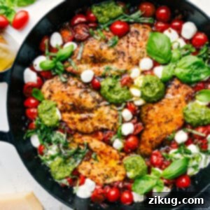 Caprese Chicken in a skillet with tomatoes, mozzarella, and basil
