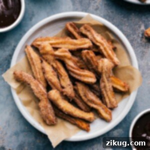 Plate of churros served with a side bowl of rich chocolate sauce.