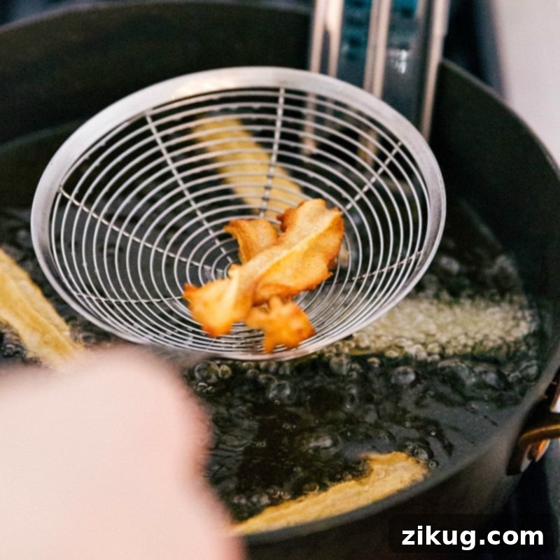 Frying Churro Dough to Golden Crispy Perfection for Ideal Texture Churro dough frying to golden perfection in hot oil, bubbling around the pastry.