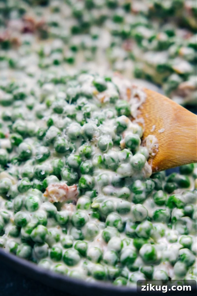 Creamed Peas: The ultimate savory Parmesan cream side dish with bacon and onions. Easy, one-pan, no thawing needed. Perfect for holidays and everyday meals. Overhead image of Creamed Peas in a serving dish, garnished