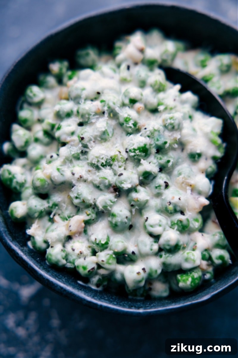 Delicious Creamed Peas ready to be served, a perfect savory side dish with bacon and Parmesan cream sauce. Up-close overhead image of the creamed peas side dish ready to be enjoyed