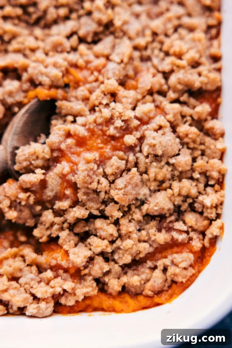 Up close overhead image of the sweet potato casserole being served from the baking dish, showing the creamy base and crunchy topping.