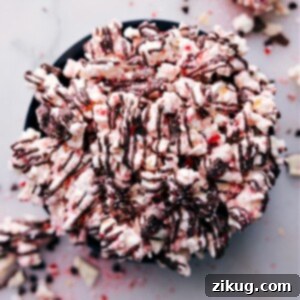 A festive bowl of Peppermint Popcorn, featuring white chocolate, crushed candy canes, and a dark chocolate drizzle.