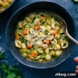 A close-up of a steaming bowl of Vegetable Pasta Soup with herb infusion