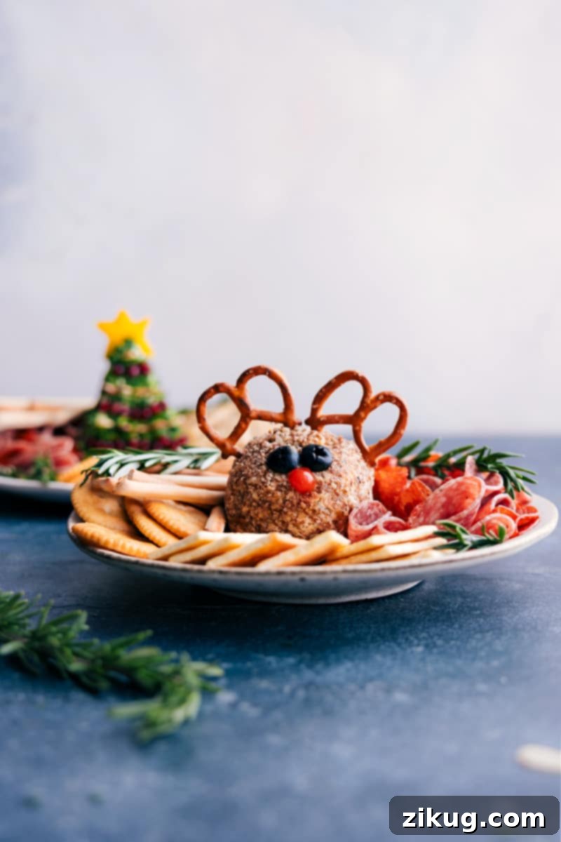 A festive platter showcasing the Rudolph Christmas Cheeseball surrounded by an assortment of crackers, vegetables, and cured meats.