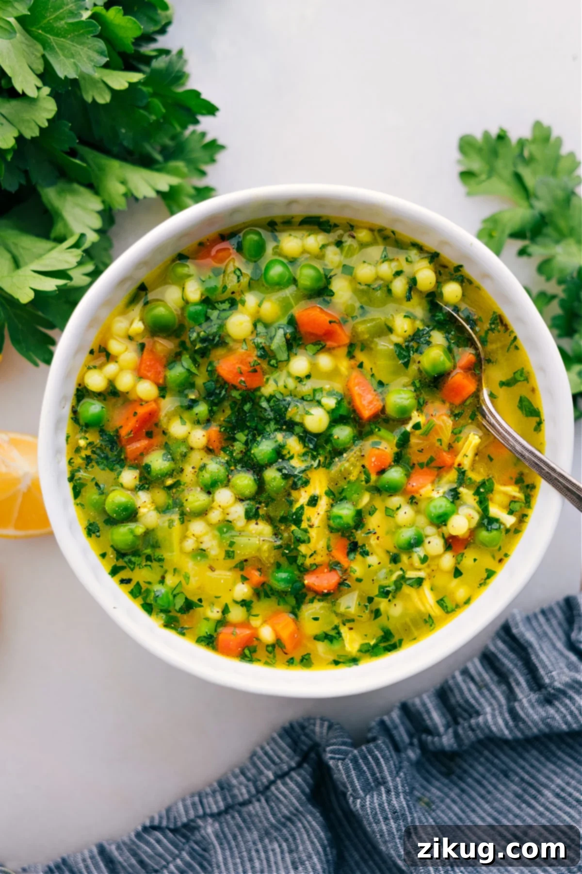 A steaming bowl of Chicken Couscous Soup, loaded with chicken, vegetables, and pearl couscous, ready to be enjoyed.