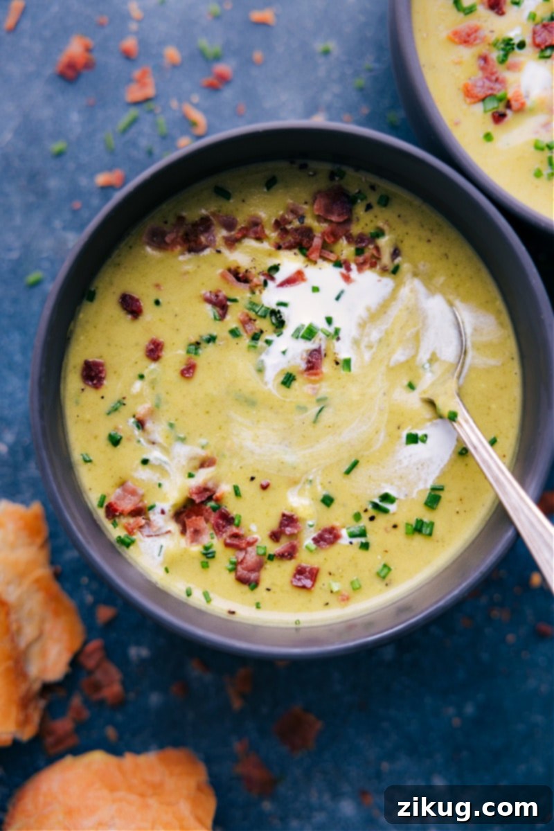 Overhead image of a bowl of broccoli soup being enjoyed with a piece of crusty bread.