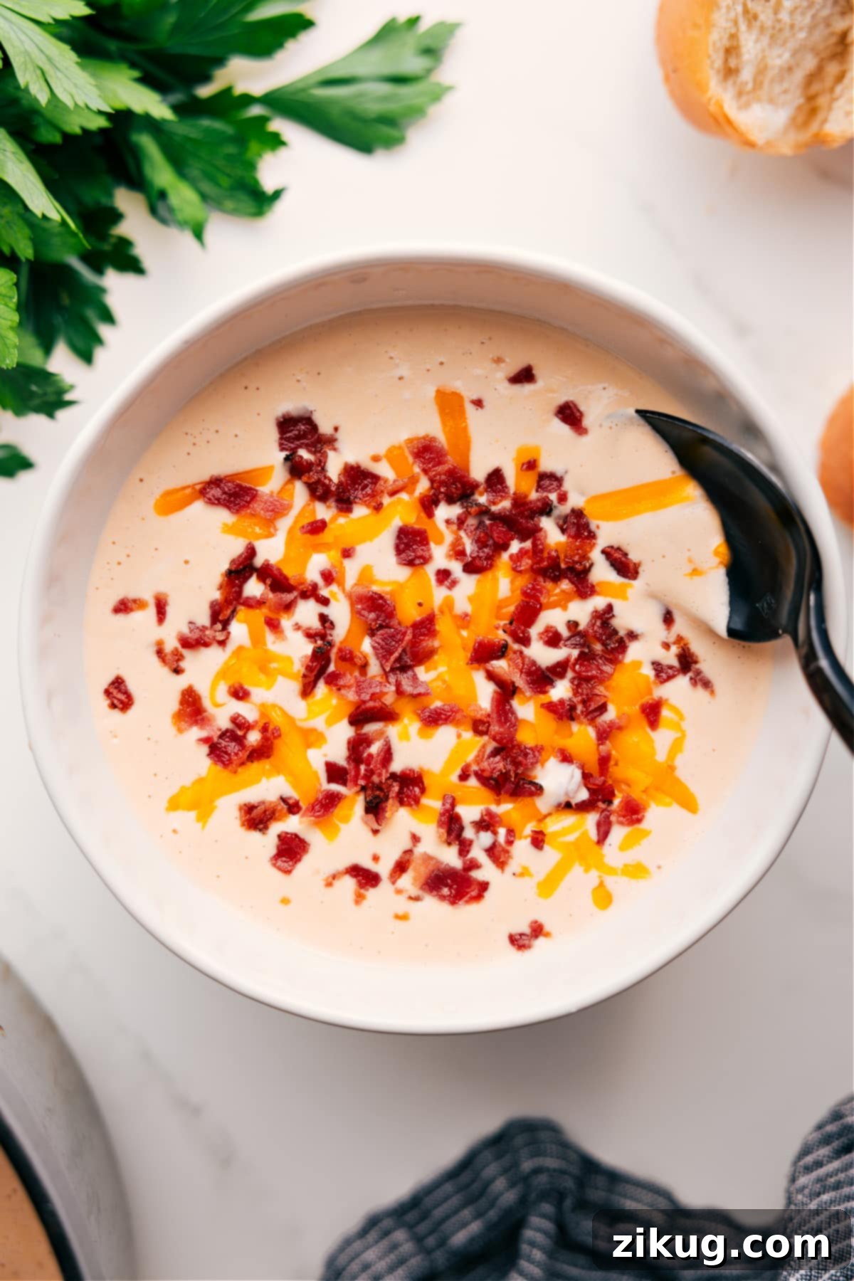 Creamy Cheesy Cauliflower Soup Recipe In A Bowl A beautiful bowl of creamy cauliflower soup, generously topped with freshly shredded sharp white cheddar cheese and crispy, crumbled bacon pieces. The soup has a rich, golden hue, indicating its cheesy goodness, and the garnishes add both visual appeal and a delightful texture contrast.