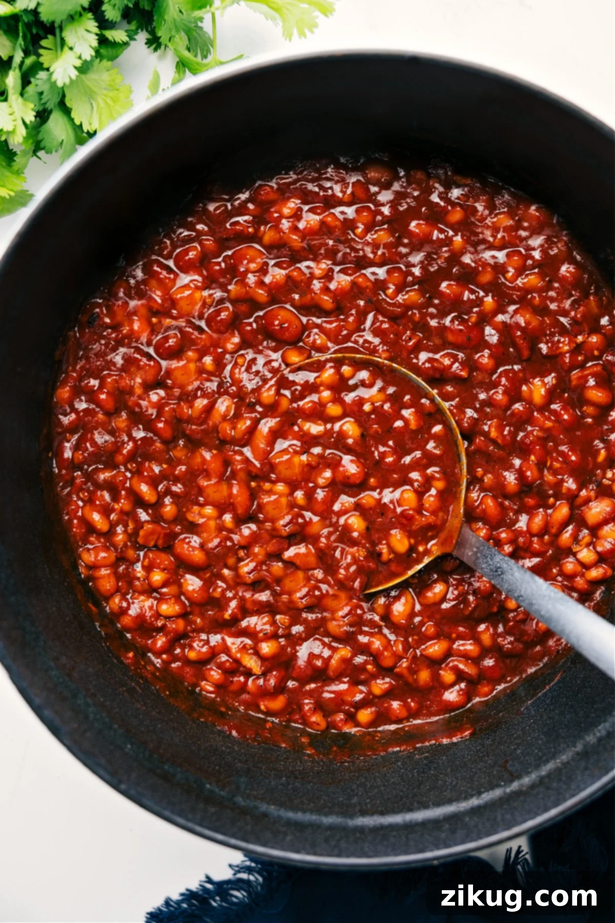 The Best Side: Baked Bean Recipe Hearty Baked Beans in a rustic pot, ready to be served, with a ladle lifting a generous scoop to show their rich texture and deep color.